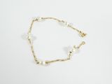 un bracelet en chaîne d'or orné de perles, sur fond blanc