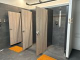 three stalls in the bathroom with orange rugs on the floor