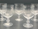 six empty wine glasses sitting on a table with a dark background