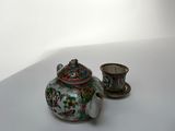 une petite théière et une tasse posées sur une table