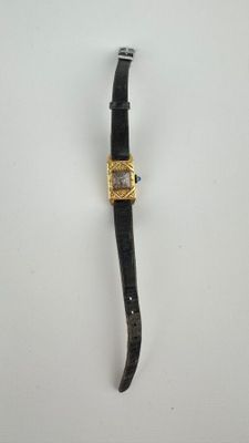 gros plan d'une montre sur une surface blanche avec un bracelet noir