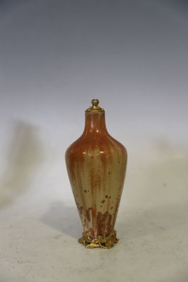 un petit vase brun posé sur une surface blanche