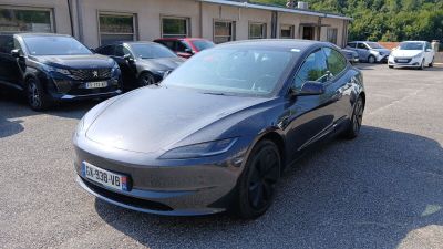 Une Tesla Model 3 garée sur un parking, avec d'autres voitures en arrière-plan