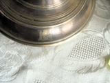 un vase en argent posé sur une table, avec une fleur dedans