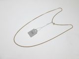 un collier en argent avec une médaille accrochée, posé sur une surface blanche