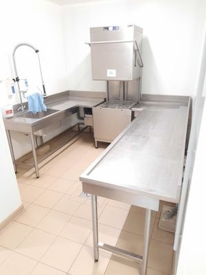 une cuisine équipée de plans de travail en inox et d'un évier