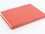 a red book with a green cover sitting on top of a white surface