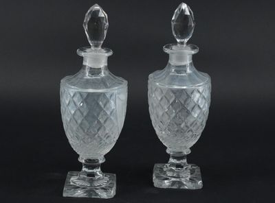 deux vases en verre transparent, surmontés d'un couvercle transparent, posés sur une surface noire