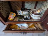 une armoire en bois avec un tiroir rempli de vaisselle et d'ustensiles