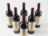 six bottles of wine are lined up in a row on a white surface