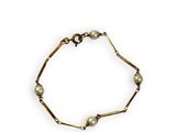 a gold bracelet with pearls on a white background