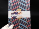a person in white gloves holding up a notebook with a blue and red design