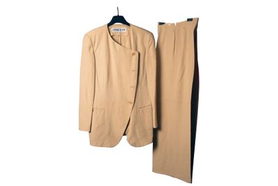 un costume et un pantalon beiges suspendus à un cintre sur un mur blanc