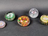 six different colored glass marbles sitting on top of a black surface