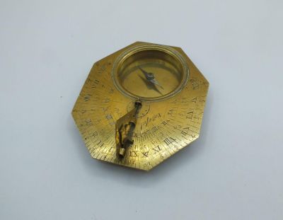 a gold plate with a compass on it on a white surface