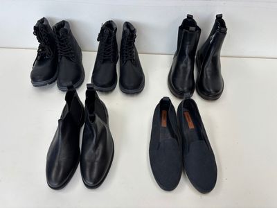 cinq paires de chaussures en cuir noir alignées sur une surface blanche
