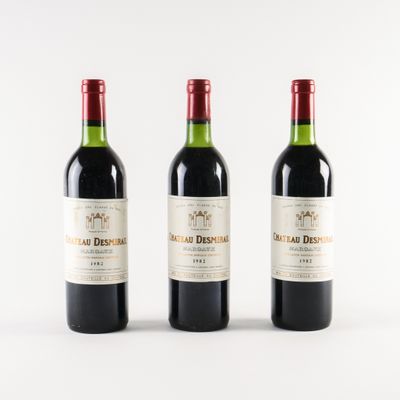 trois bouteilles de vin rouge posées l'une à côté de l'autre sur une surface blanche