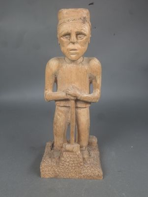 statue d'un homme coiffé d'un chapeau, les bras croisés