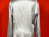 a silver jacket on a mannequin stand against a red wall