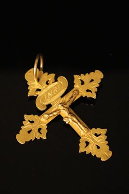 a close up of a gold cross on a black surface