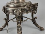 an antique silver plate on a stand with a bird on it