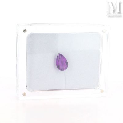 a purple stone in a clear box on a white surface