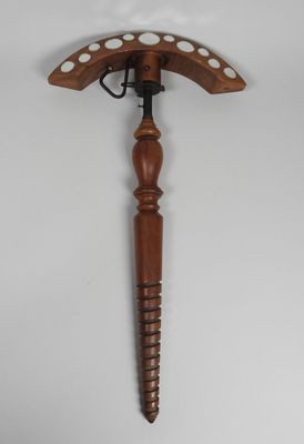an old wooden hammer with holes on it hanging on a wall