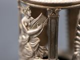 a silver vase that has a statue on top of it