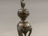 a bronze candle holder with a bird on top of it