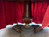 une photo d'une table en bois avec un rideau rouge en arrière-plan