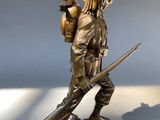 bronze statue of a man with a gun and a dog on a rock