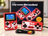 une petite console de jeux rouge posée sur une table à côté d'une boîte
