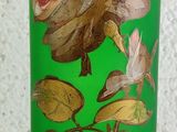 a green vase with a rose on it on a table