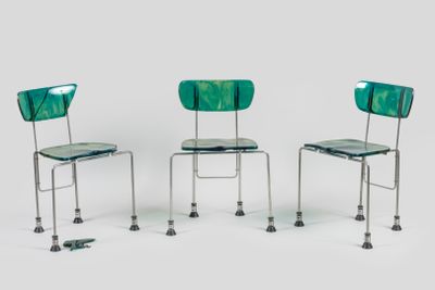 trois chaises vertes placées les unes à côté des autres sur une surface blanche