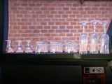 bottles and glasses are lined up on a window sill in front of a brick wall