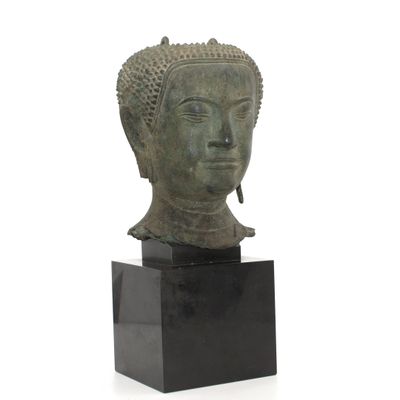 Tête de bouddha en bronze, le visage serein, les cheveux en …