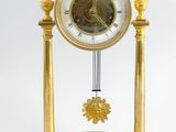 a gold clock with a pendulum on a stand