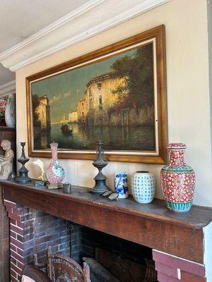 a painting on the wall above a fireplace with vases on it