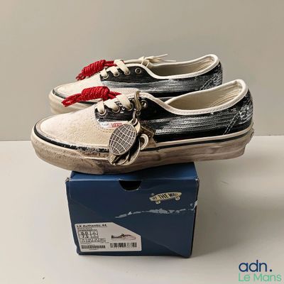 une paire de baskets sans lacets « Vans » dans une boîte posée sur une table