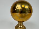 a shiny gold ball on a gold pedestal on a white background