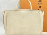 a white handbag sitting on top of a table next to a box