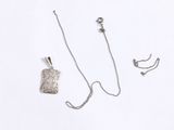 a silver necklace and earring set on a white surface