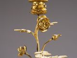 a gold plated candle holder with flowers and leaves on a table