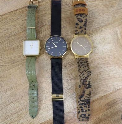 three different watches sitting on a wooden surface with a leopard print strap