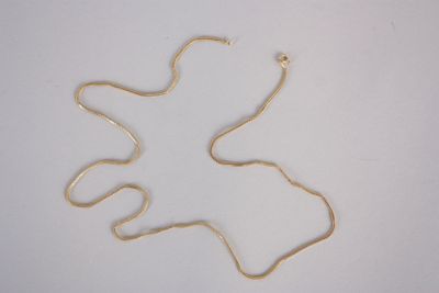 une photo d'un collier en or posé sur une surface blanche