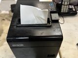 a black printer sitting on a counter with a cell phone in the background