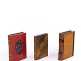 three miniature books sitting next to each other on a white surface