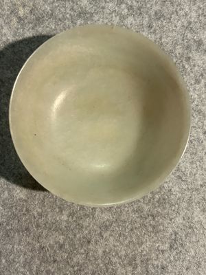 a white bowl sitting on a table with a shadow on it