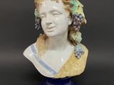 a close up of a ceramic bust of a woman with grapes on her head