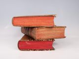 several old books stacked on top of each other on a white surface